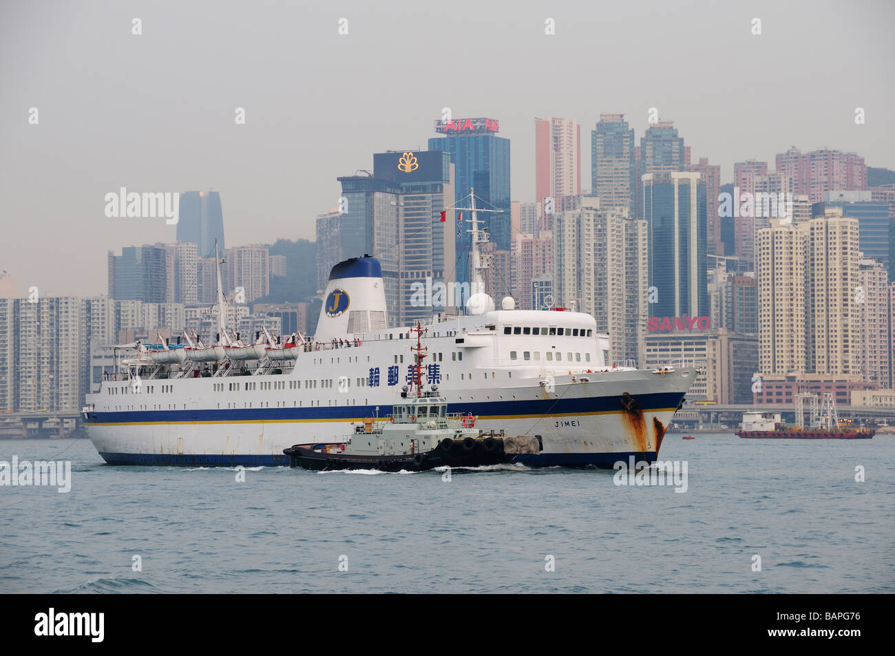 Motorschiff Jimei und Schlepper im Hafen von Hong Kong Stockfoto