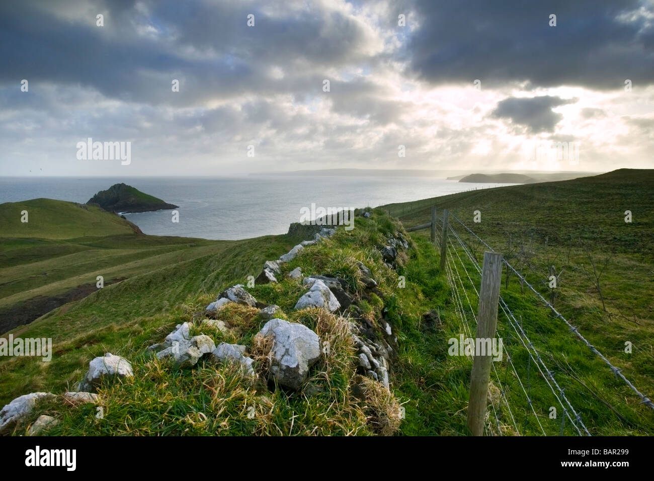 Blick auf die Strahlen der Sonne durch die Wolken mit Felsen und Zäune im Vordergrund piercing. Stockfoto