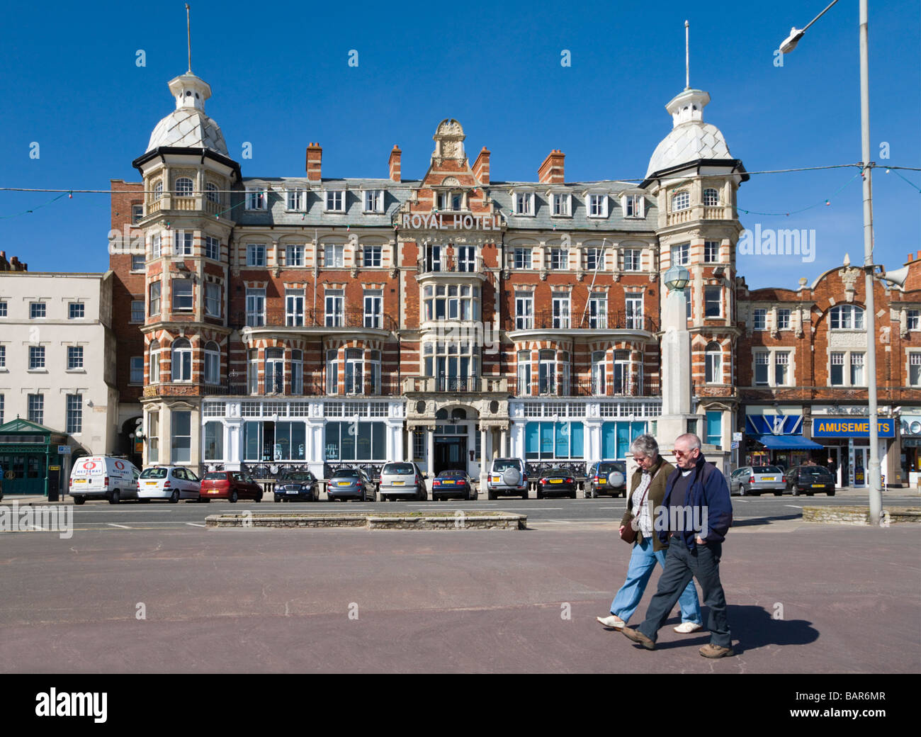 Ein älteres paar zu Fuß auf Weymouth Esplanade vor dem Royal Hotel. Weymouth, Dorset, UK. Stockfoto