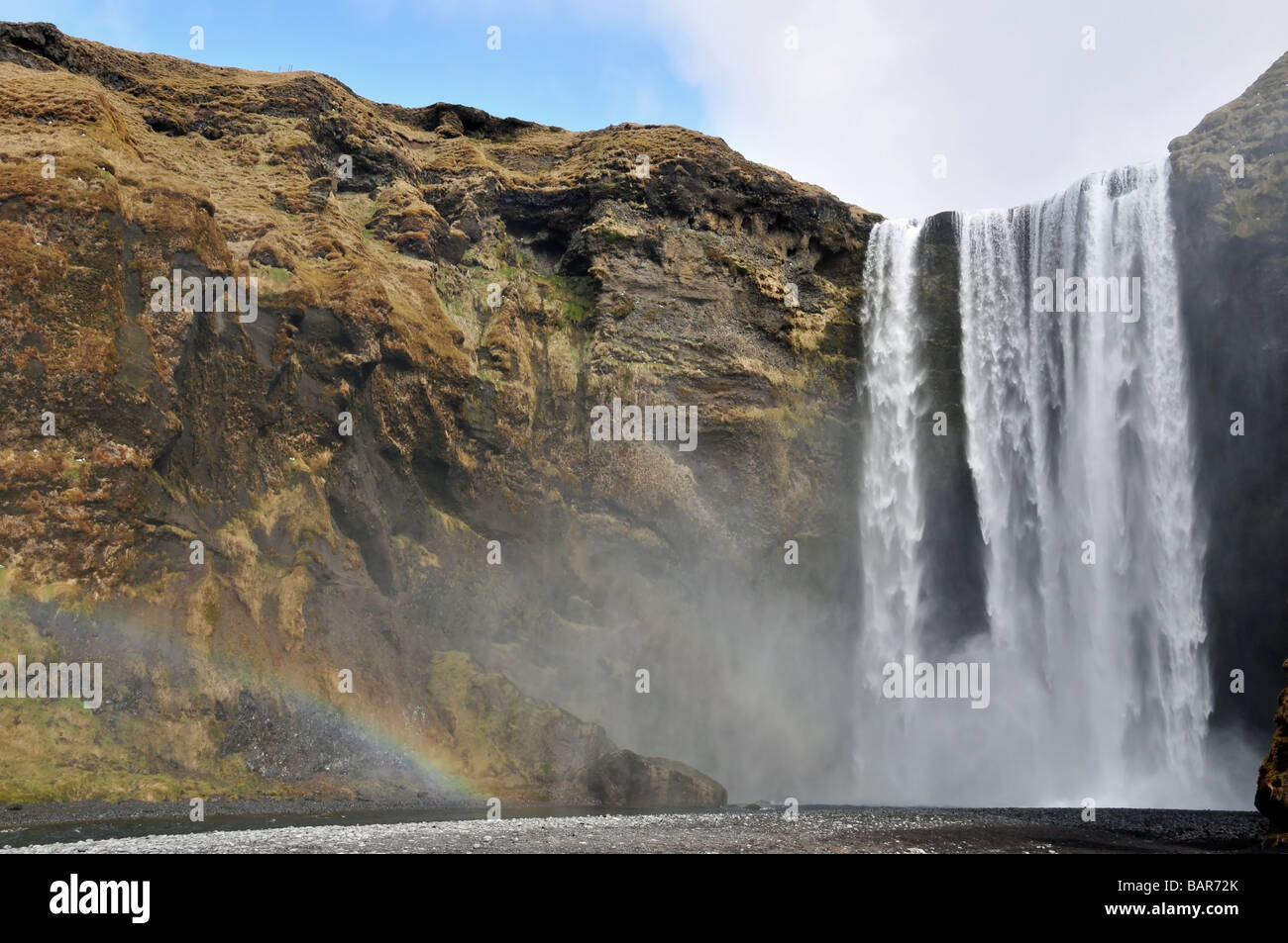 Weitwinkel-Frontalansicht der Skogafoss-Wasserfall, mit einem Regenbogen in der Gischt an den Fuß, Skogar, Southern Island Stockfoto