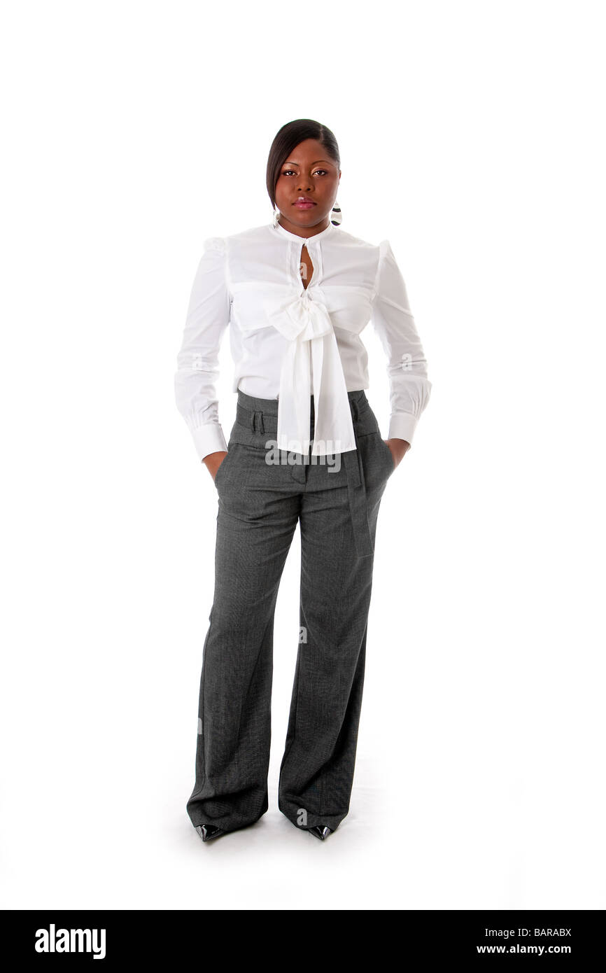 Schöne afrikanische amerikanische Geschäftsfrau mit Haltung gekleidet in ein weißes Hemd und graue Hose stehend Hände in Tasche Stockfoto