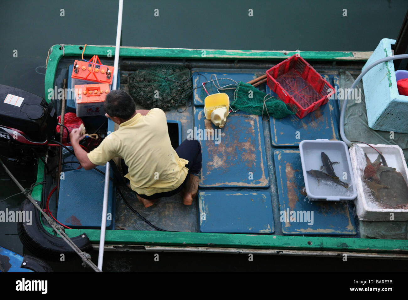 Es ist ein Fischer zurück in den Hafen zu verkaufen seine Fische. Es Blick von oben. Er hat eine grüne Boot und wenige Fische in Kunststoff-box Stockfoto