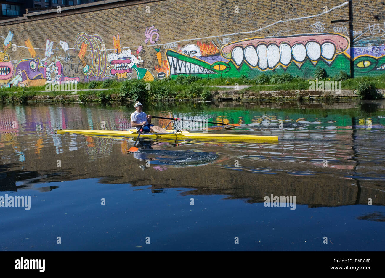 Kanufahrer auf Fluss Lee London neben Wand mit Graffiti mit Krokodilen. Stockfoto