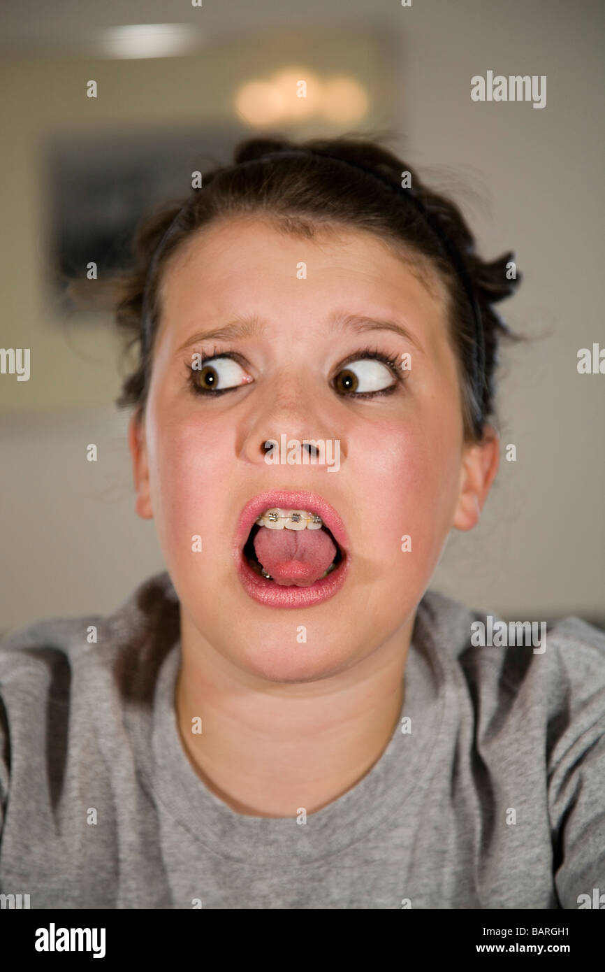 Ein ziemlich junges Mädchen tragen Hosenträger zeigt einen Blick von Angst oder Schrecken und zeigt ihr die Zunge zeigen Stockfoto