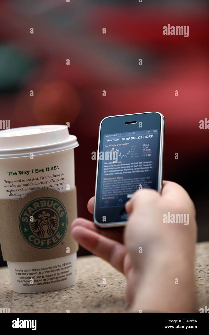 Mann überprüfen Starbucks Lager von einem iPhone Stockfoto
