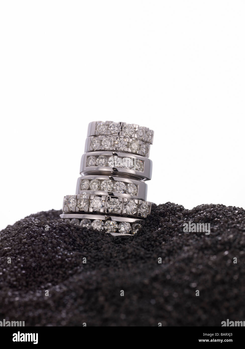 Gestapelte Diamantringe auf schwarzem sand Stockfoto