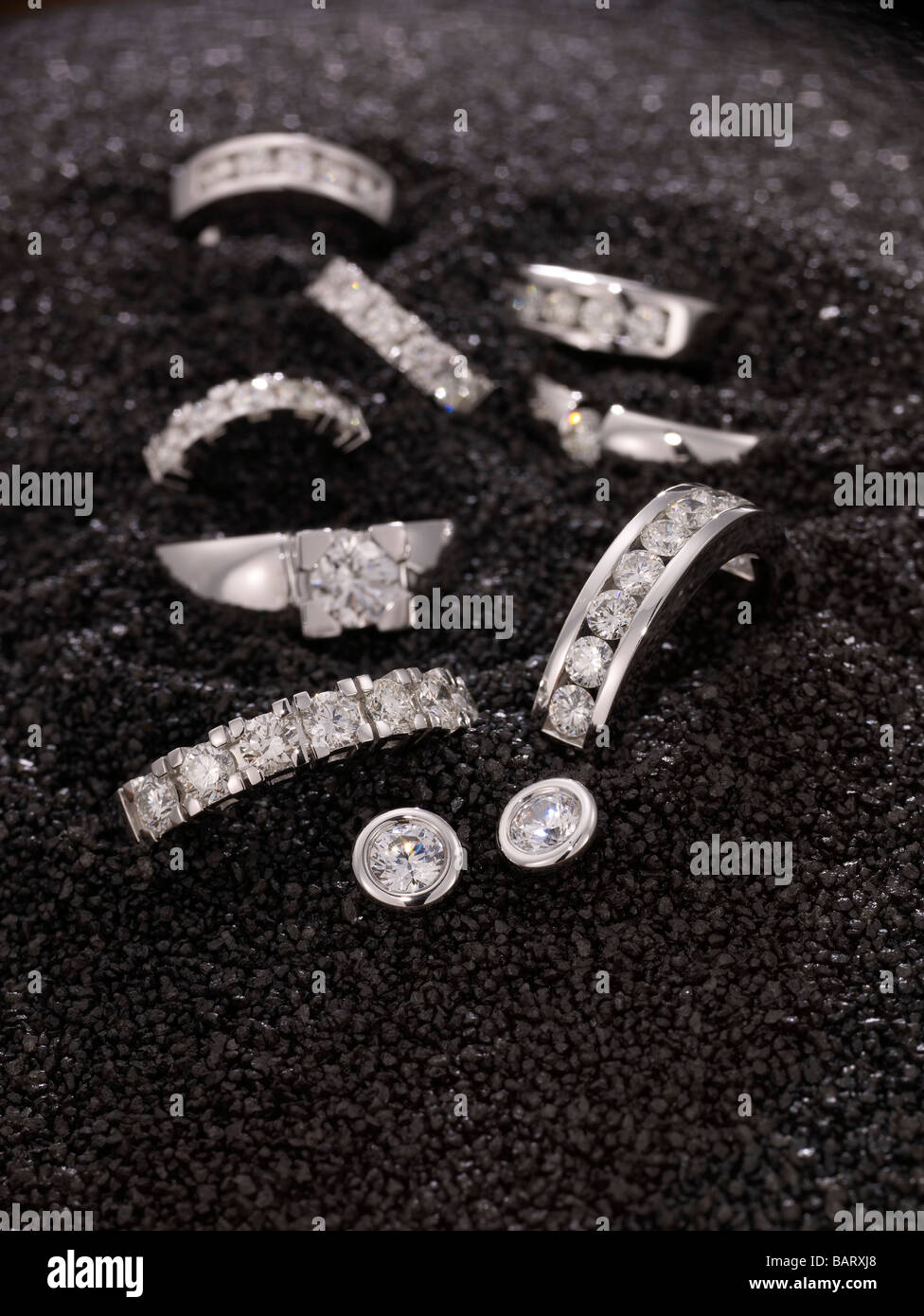 Diamant-Ringe und Ohrringe auf schwarzem sand Stockfoto