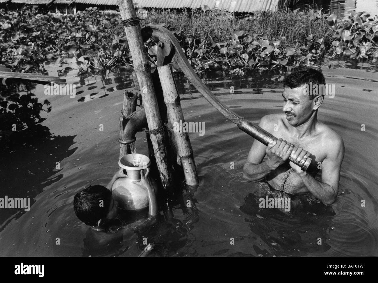 Nr. 4, Dhaka, Bangladesch Sept 1998 Slum: Vater und Sohn frisches Wasser schöpfen aus einer der wenigen Pumpen nicht durch Hochwasser überflutet. Stockfoto