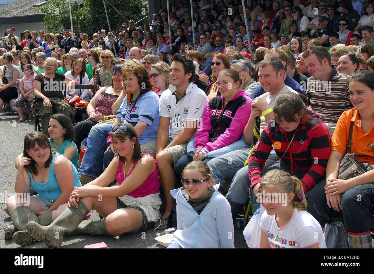 Masse der bunt gekleidete junge Menschen sitzen in einem Publikum in ein outdoor-Event. Stockfoto