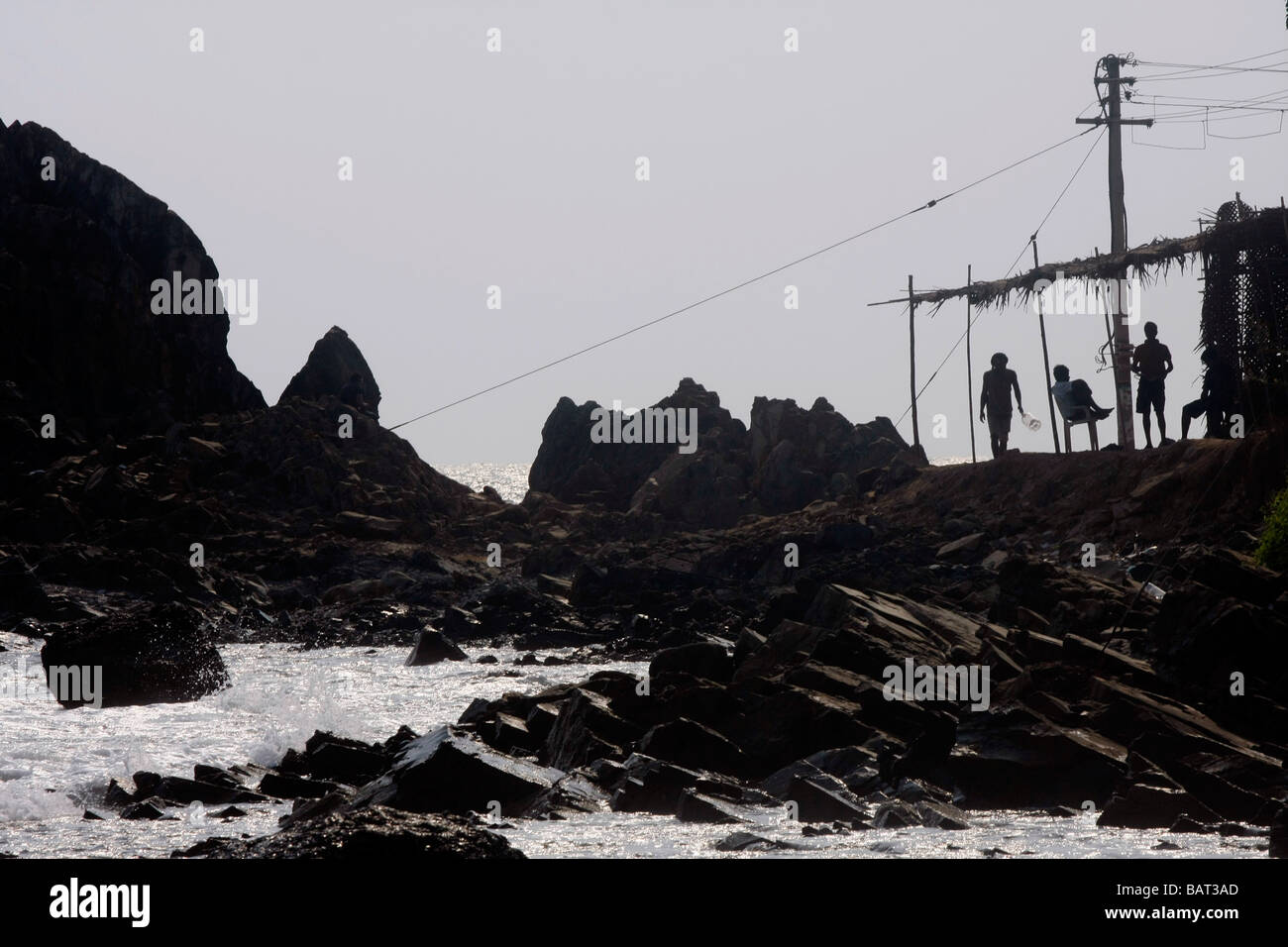 Menschen laufen entlang der felsigen Küste in der Nähe von Arambol Beach im nördlichen Goa in Indien. Stockfoto