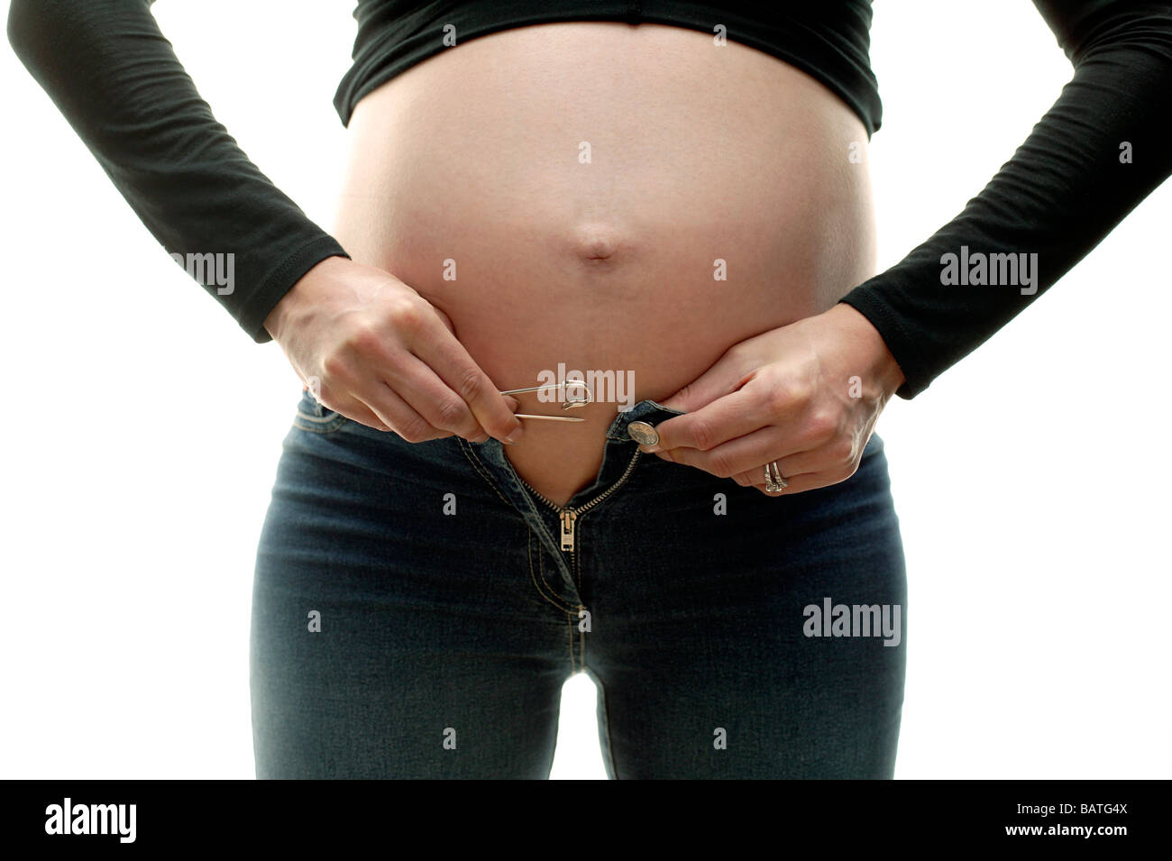 Schwangere Frau versucht, ihre Jeans über ihren geschwollenen Bauch befestigen. Sie ist in ihrem dritten Trimester. Stockfoto