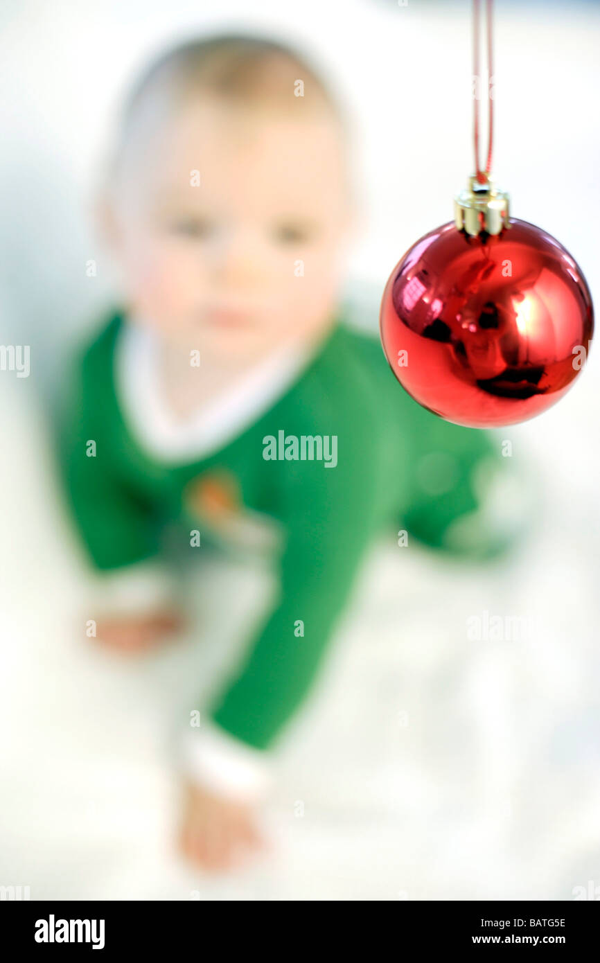 Baby Junge eine Weihnachtskugel betrachten. Er ist neun Monate alt. Stockfoto
