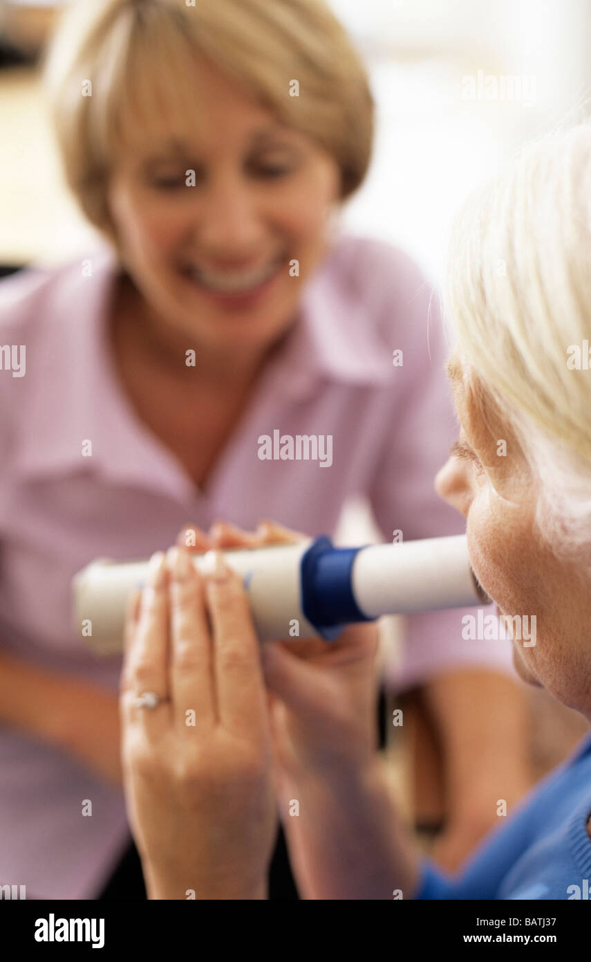 Lungenfunktionstest. 63 Jahre alte Frau ein Peak Flow meter(spirometer) einzuhauchen. Stockfoto