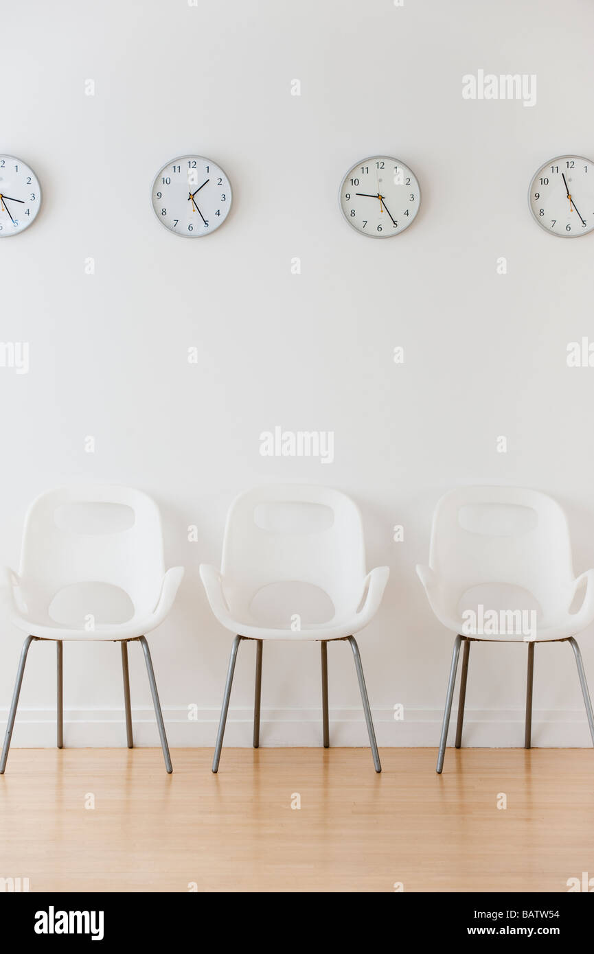 Reihe von Stühlen im Wartezimmer unter Uhren Zeitzonen anzeigen Stockfoto