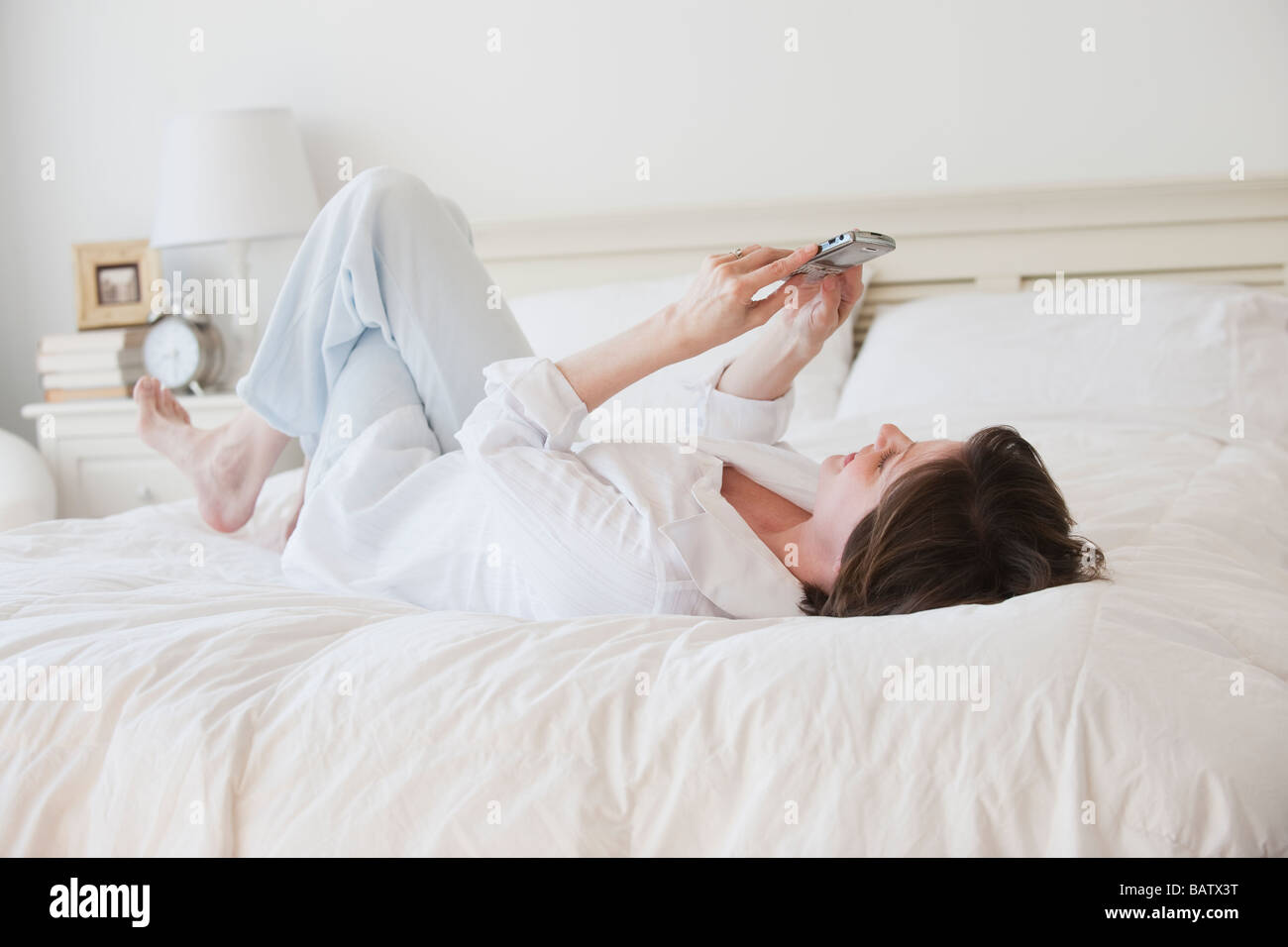 Reife Frau Textnachrichten im Bett Stockfoto