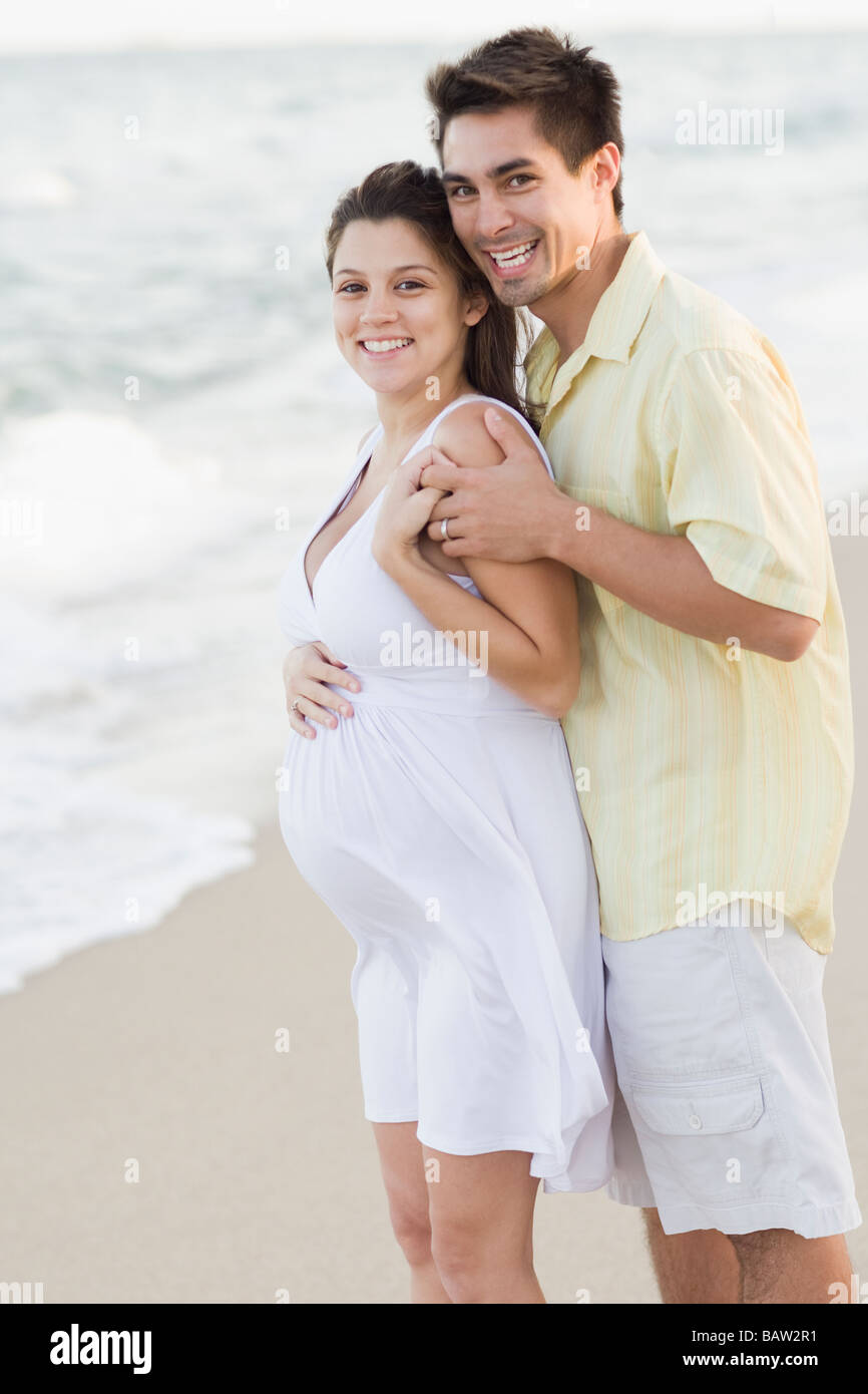 Mann umarmt schwangere Frau am Strand Stockfoto