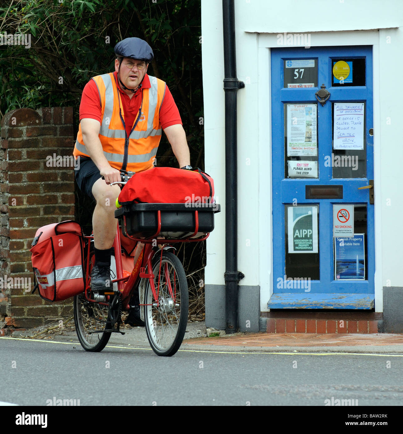 Postbote Radfahren auf seine Royal Mail Route Kopfschutz tragen  Stockfotografie - Alamy