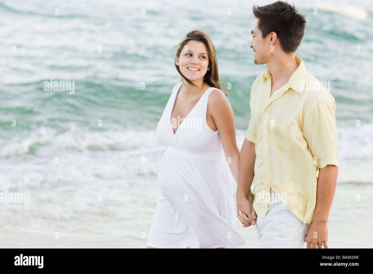 Mann, Hand in Hand mit schwangeren Frau am Strand Stockfoto