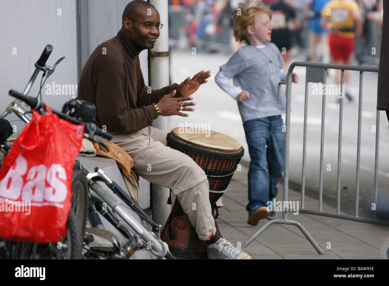 Schlagzeuger Mann Musiker schwarze Trommeln sitzen am Rotterdamer Straße Stadtmarathon machen Lärm Musik Rhythmus Spaß Läufer laufen Stockfoto