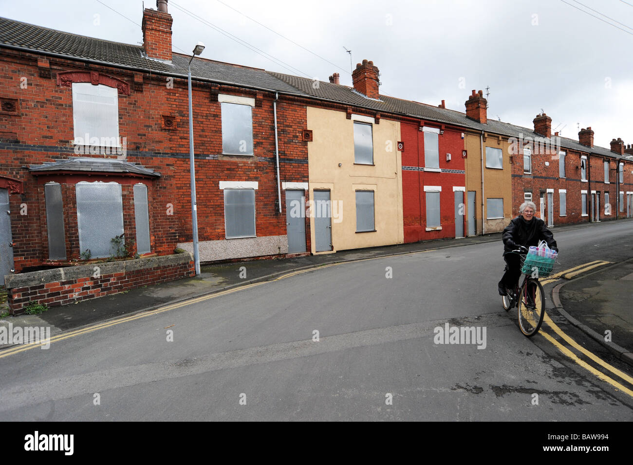 Eine ältere Frau Zyklen vorbei an heruntergekommenen Häusern bereit für den Abriss, Goole in der Nähe von Hull UK Stockfoto