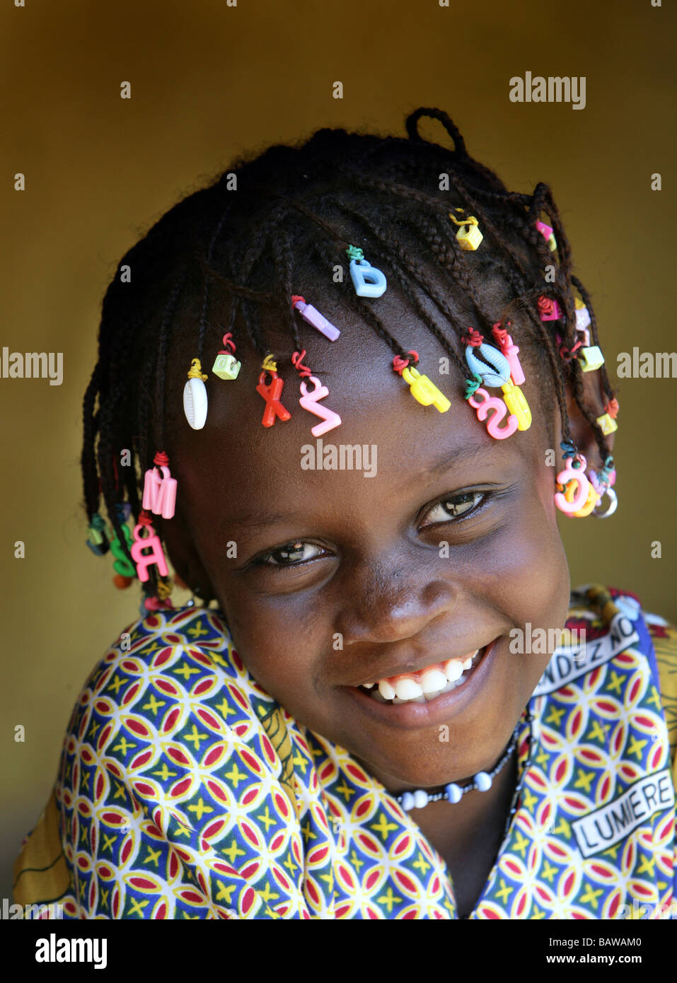 lächelndes Mädchen mit Buchstaben in ihre Dreadlocks, Guinea, Westafrika Stockfoto