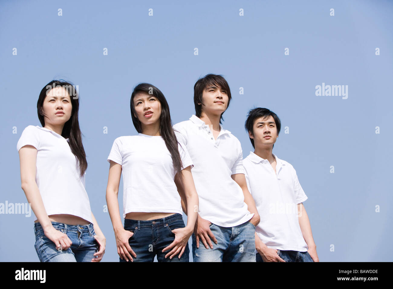 Vier junge Erwachsene stehend mit Händen in den Taschen Stockfoto