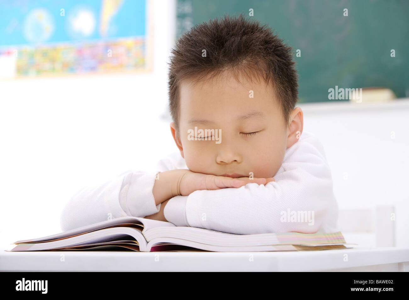 Junge beim Einschlafen an seinem Schreibtisch im Klassenzimmer Stockfoto