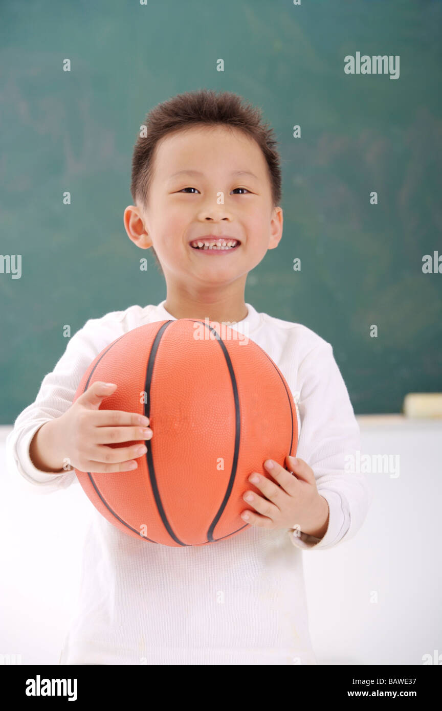 Junge stand vor Tafel hält einen basketball Stockfoto