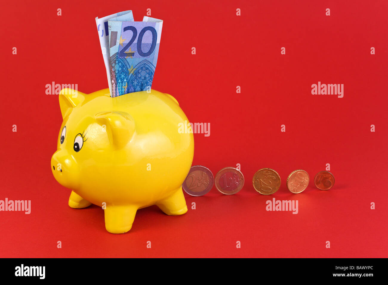 interessieren Sie Konzept - gelbe Sparschwein mit 20 Euro-Schein in Schlitz und verschiedene Münzen dahinter Stockfoto