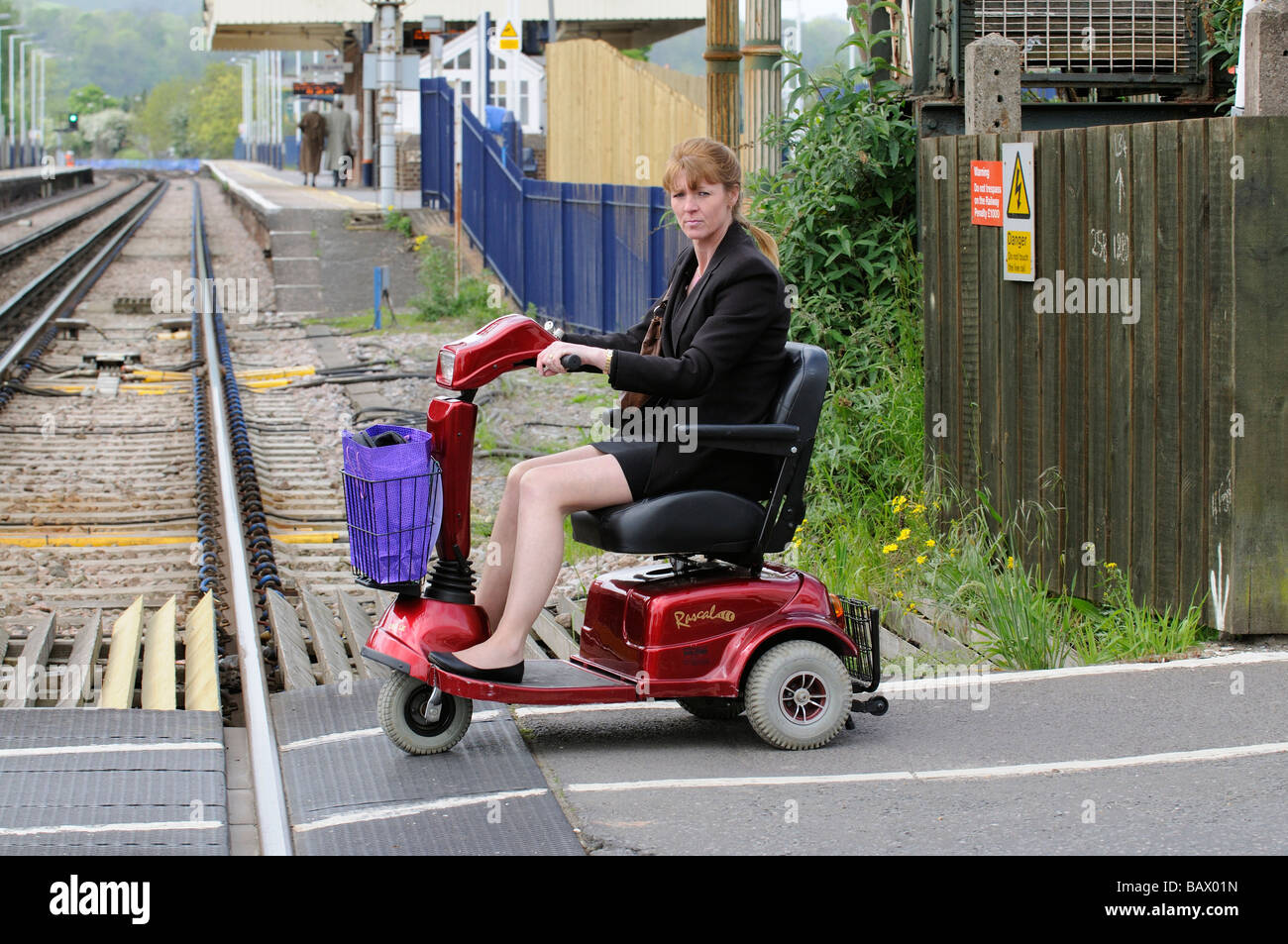 Autofahrerin ihr Elektromobil über einen Bahnübergang route England UK Stockfoto