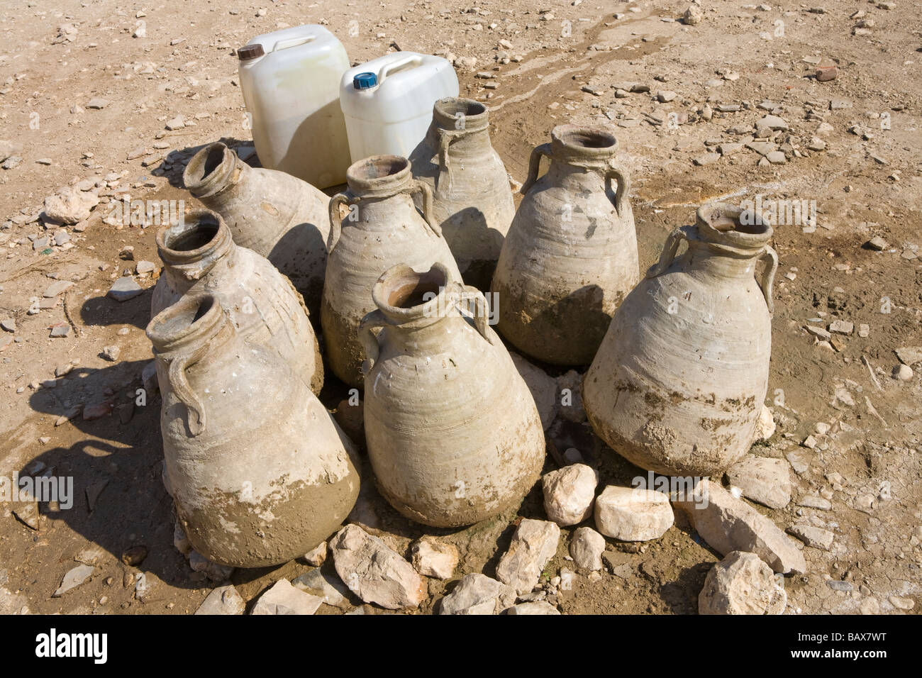 Traditionelle Keramik Wasserkrüge und moderne Kunststoff-Behälter stehend auf dem Wüstenboden, Deir el Medina, Ägypten, Afrika Stockfoto