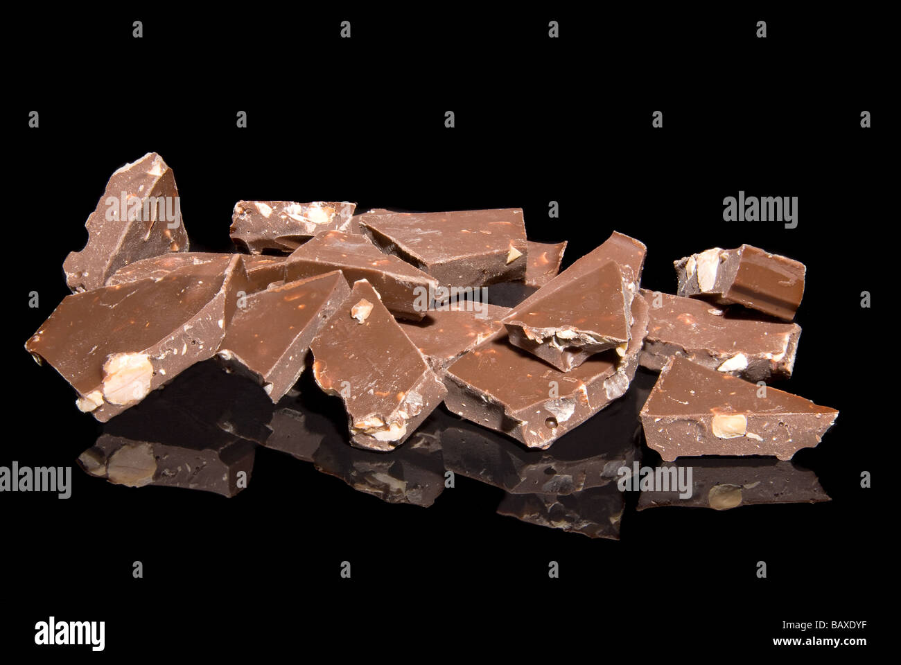 Stücke von Milchschokolade mit Mandeln auf einer schwarzen reflektierenden Oberfläche Stockfoto