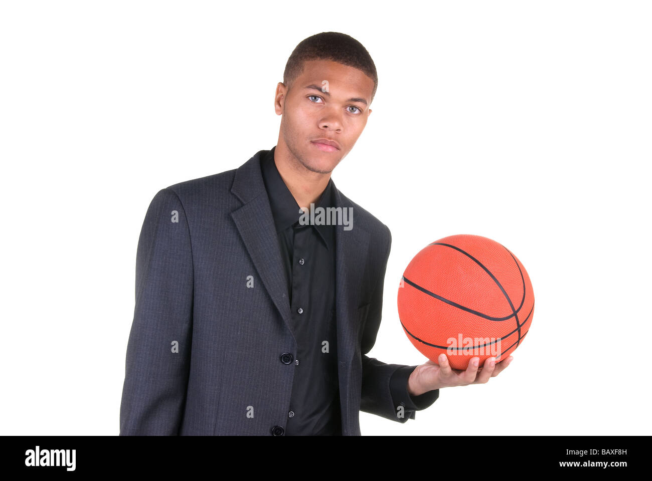 Ein afrikanischer US-amerikanischer Basketballspieler hält einen Basketball während des Tragens seine casual Business-Anzug Stockfoto