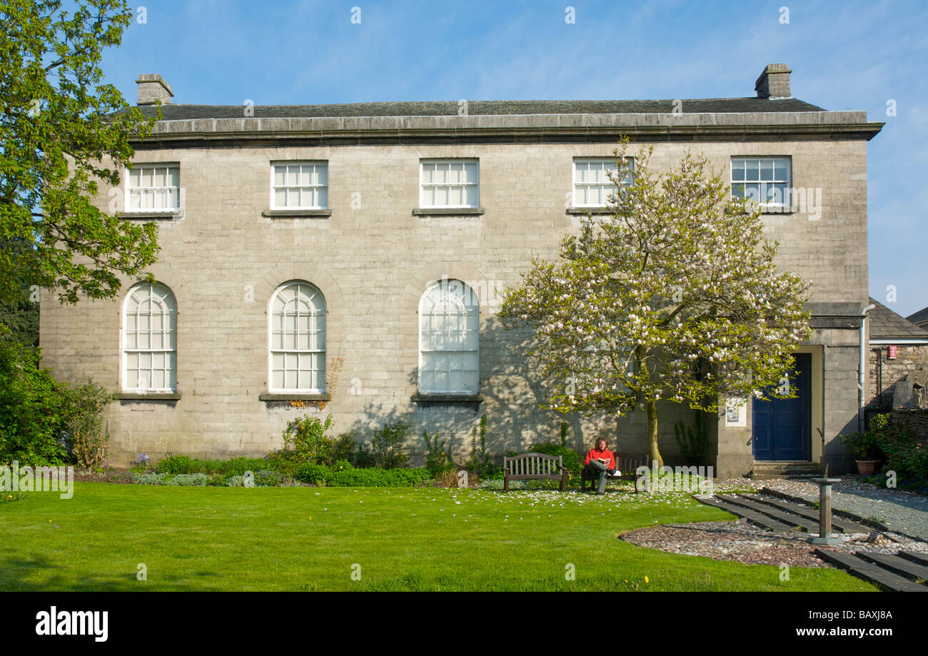 Mann liest Buch vor der Quaker Meeting House in Kendal, Cumbria, England UK Stockfoto
