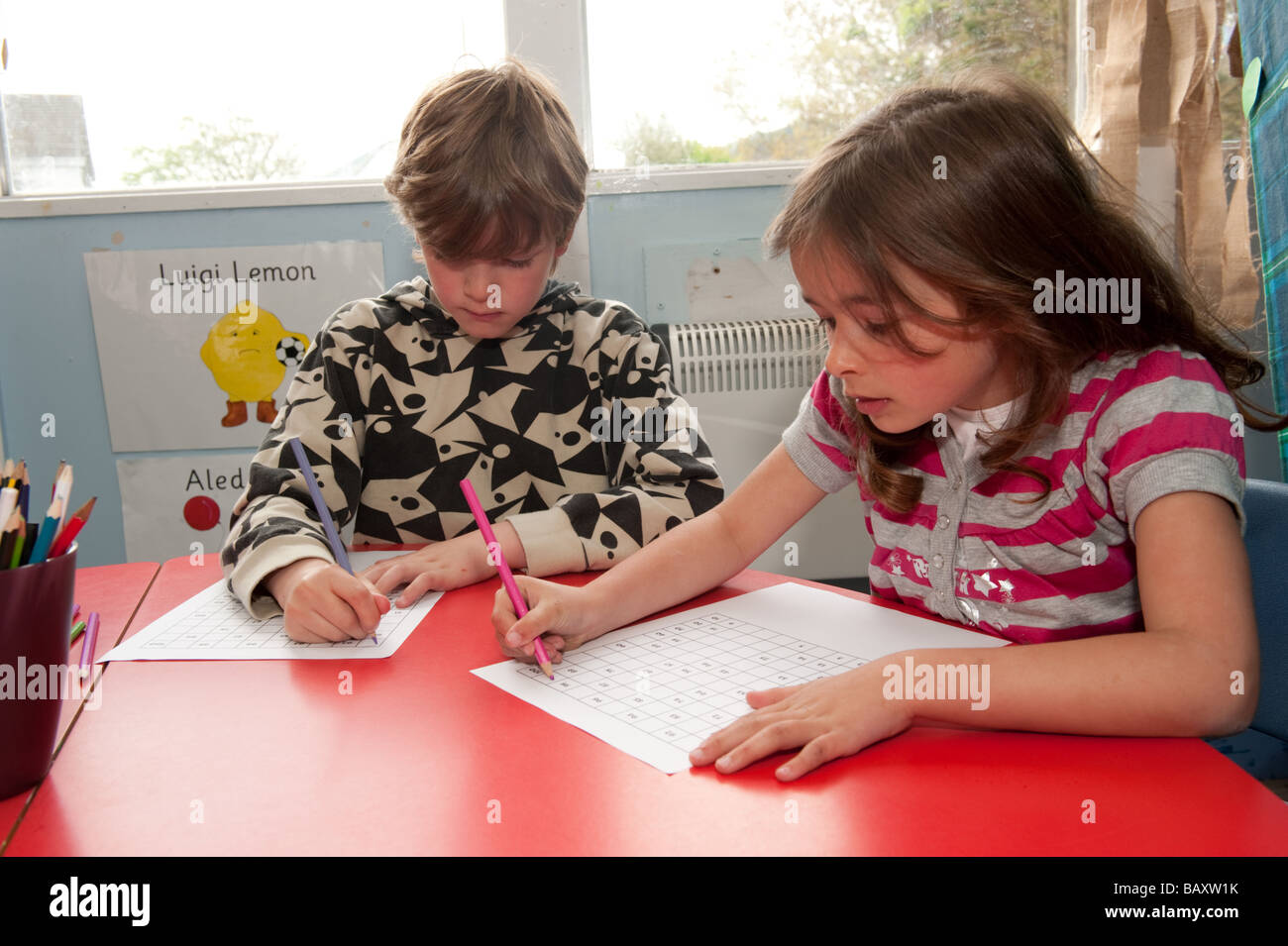 Zwei Kinder im Grundschulalter Key Stage 1 KS1 arbeitet an einem Mathematik-puzzle in einem Klassenzimmer Wales UK Stockfoto