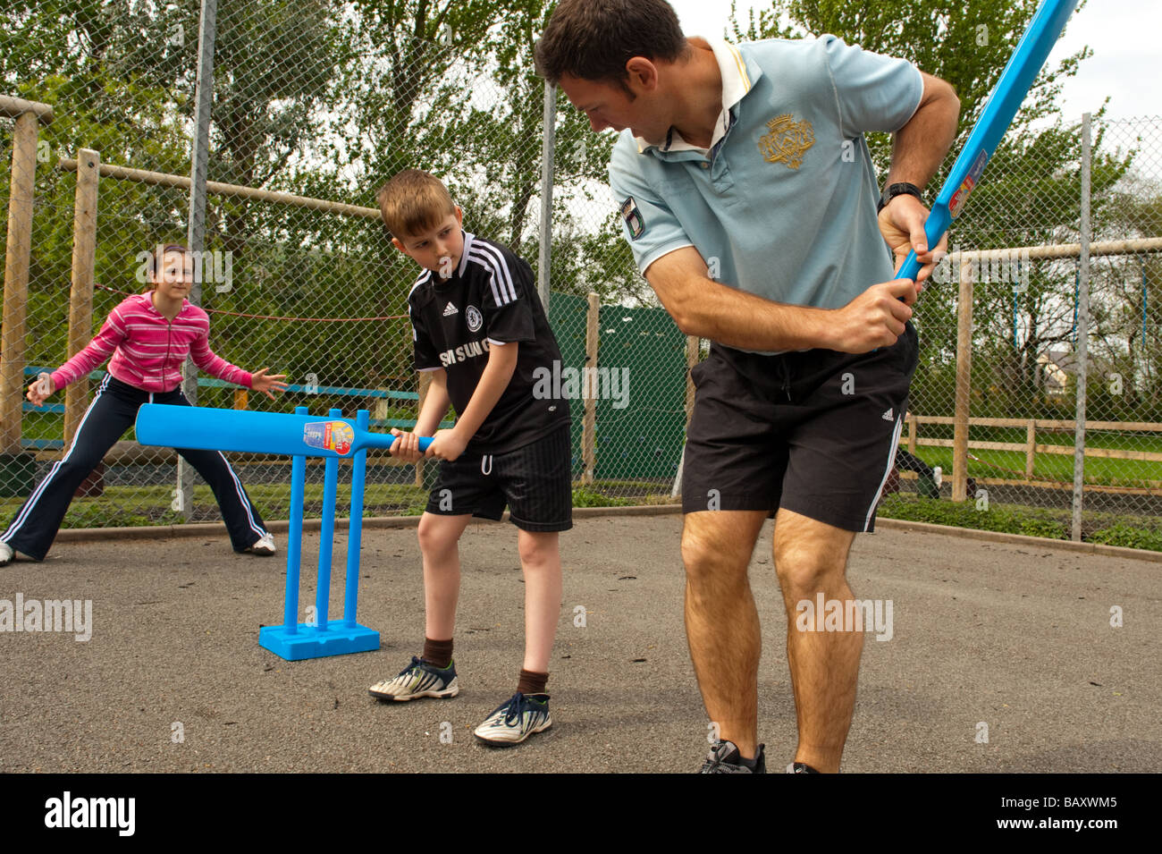 Männliche Grundschullehrer Cricket Fähigkeiten-Unterricht mit Kindern im Rahmen des Sportunterrichts in einer Schule Wales UK Stockfoto