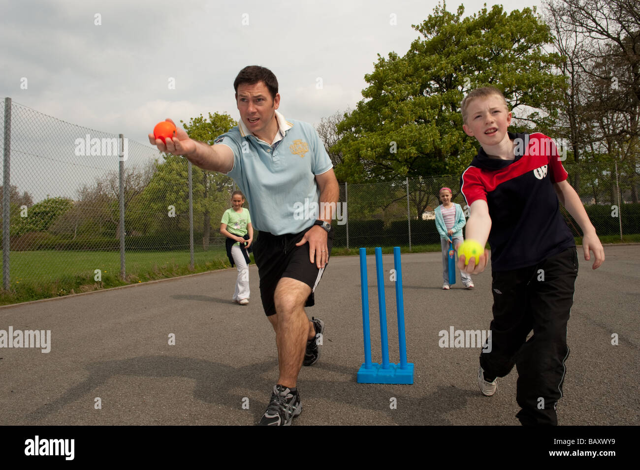 Männliche Grundschullehrer Cricket Fähigkeiten-Unterricht mit Kindern im Rahmen des Sportunterrichts in einer Schule Wales UK Stockfoto