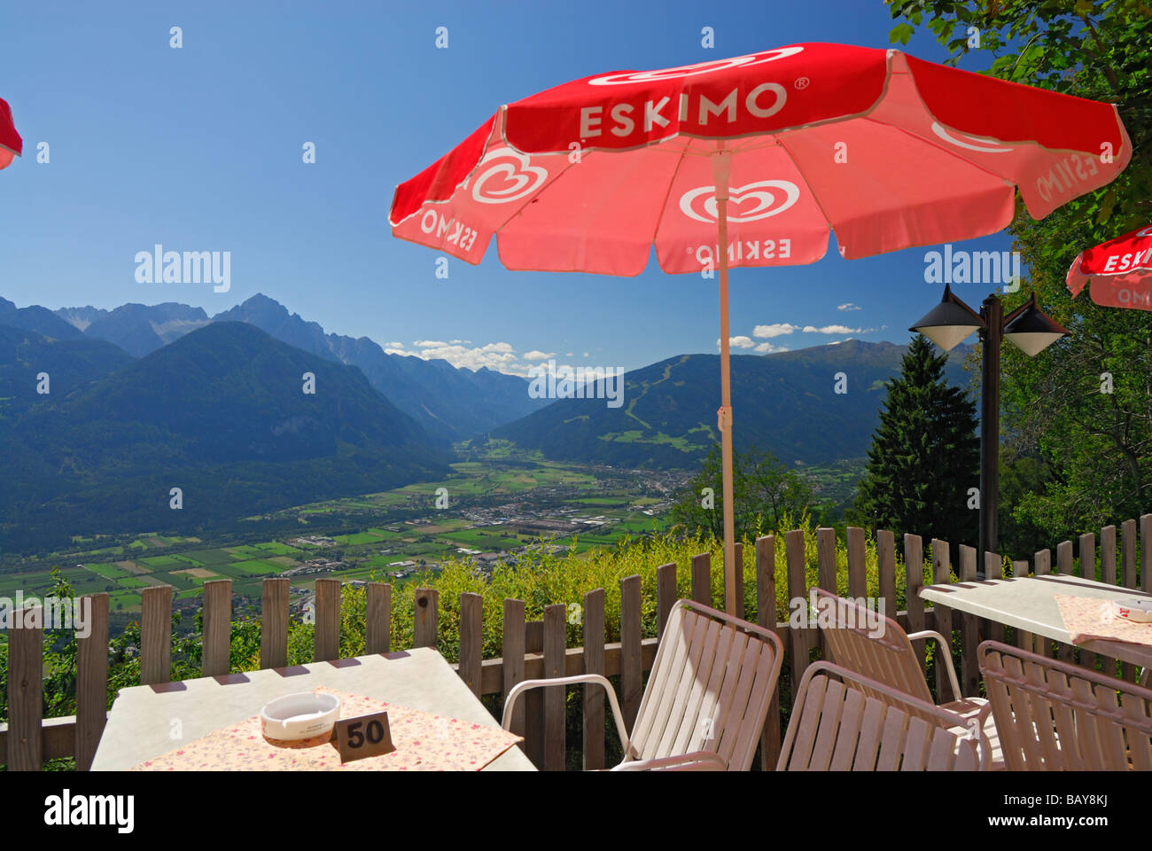 Tisch und Stühlen unter roten Sonnenschirm mit Blick auf Tal von Lienz und Lienzer Dolomiten Bereich, Schobergruppe Bereich, Hohe Tauern ra Stockfoto
