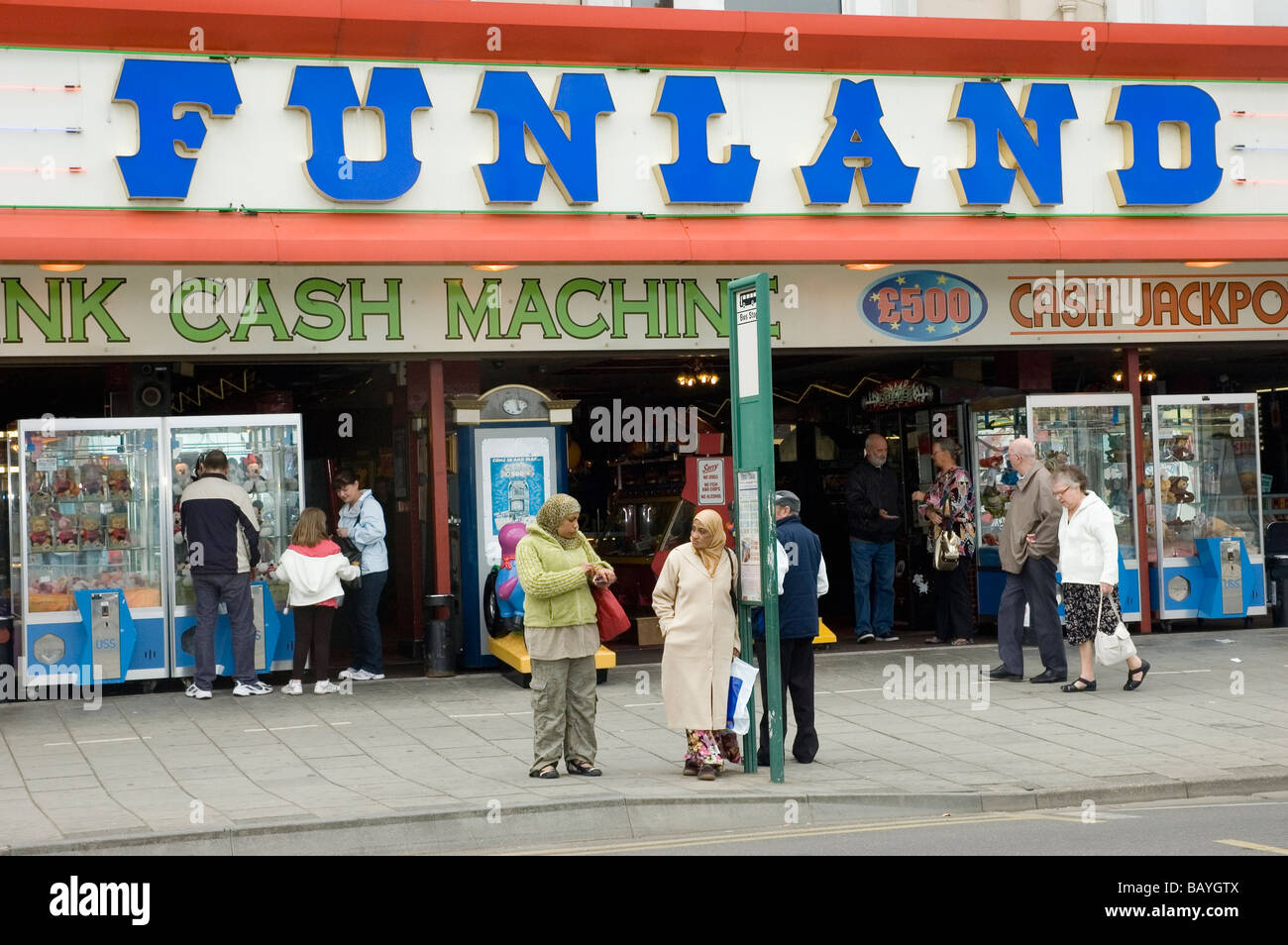 Menschen warten an einer Bushaltestelle außerhalb der Funland-Spielhalle in Skegness Stockfoto