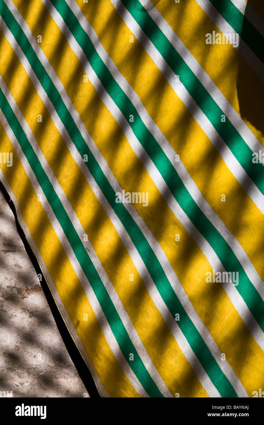 Grafik gesprenkelt vom Dach der Medina Schatten auf einen knallgelben & grün gestreift, Wasser, Beweis plane Tisch Stockfoto