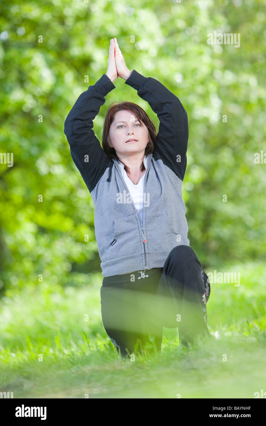 Ein weiblicher Yoga-Lehrer während einer Outdoor-Klasse in der englischen Landschaft Stockfoto