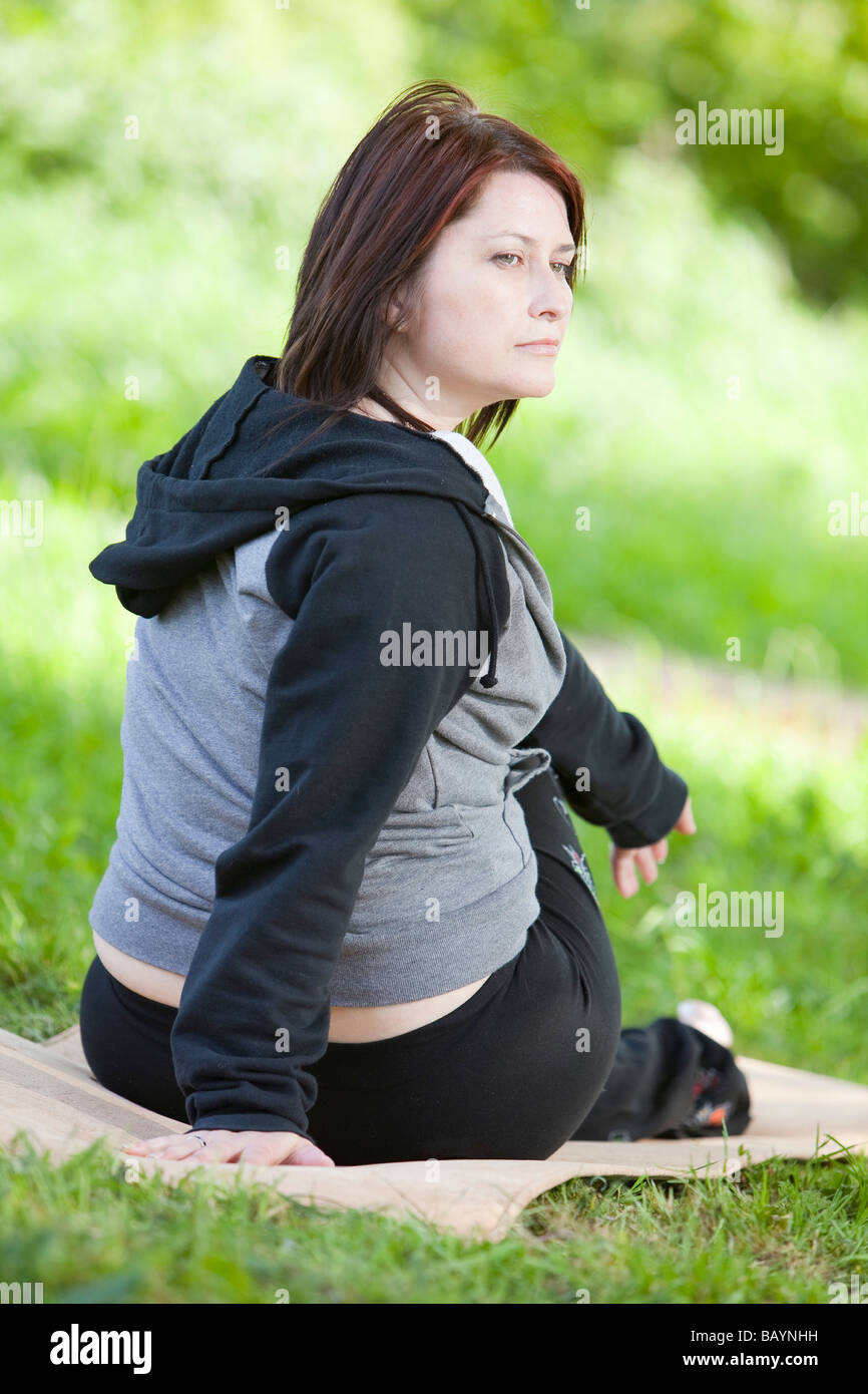 Ein weiblicher Yoga-Lehrer während einer Outdoor-Klasse in der englischen Landschaft Stockfoto