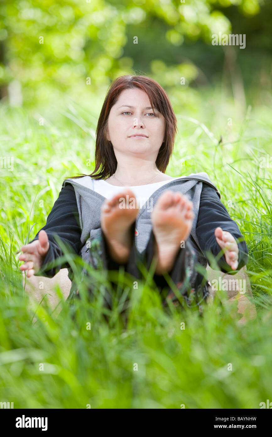 Ein weiblicher Yoga-Lehrer während einer Outdoor-Klasse in der englischen Landschaft Stockfoto