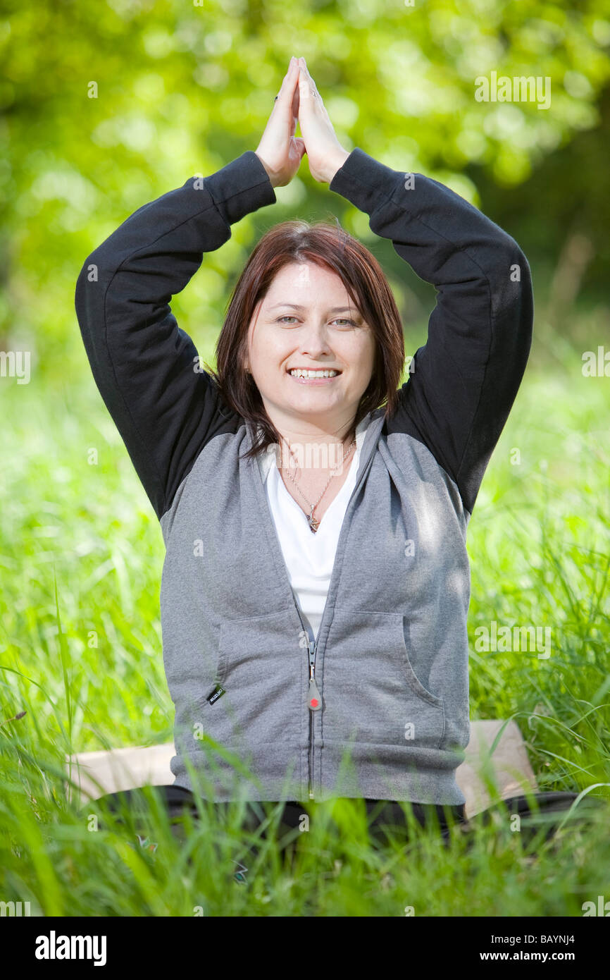 Ein weiblicher Yoga-Lehrer während einer Outdoor-Klasse in der englischen Landschaft Stockfoto