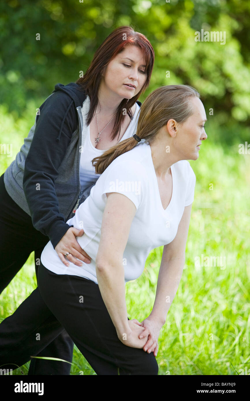 Ein weiblicher Yogalehrer mit einer Schülerin während einer Outdoor-Klasse in der englischen Landschaft Stockfoto