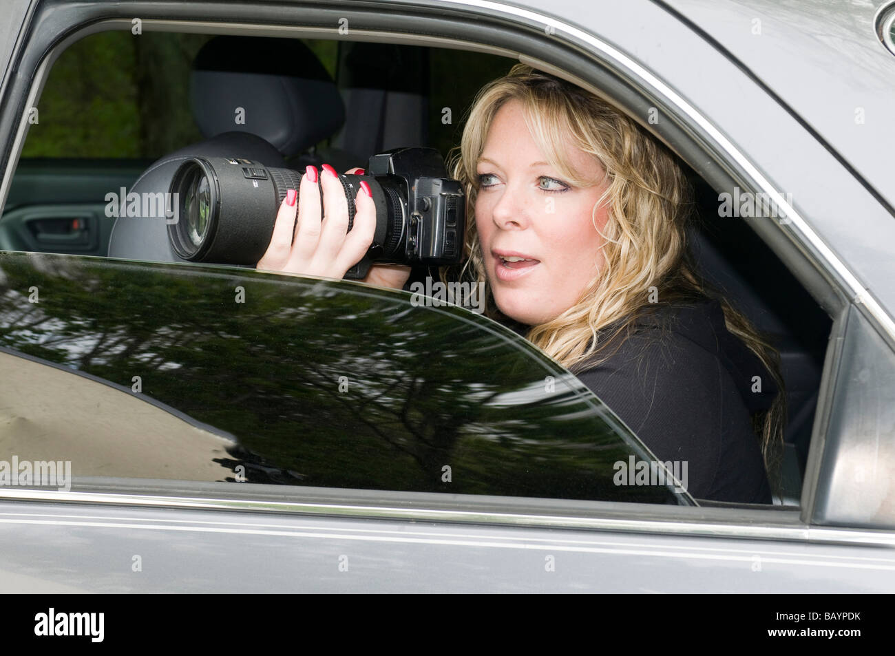 weiblichen Privatdetektiv oder Spion oder Geheimagenten fotografieren aus dem Auto Stockfoto