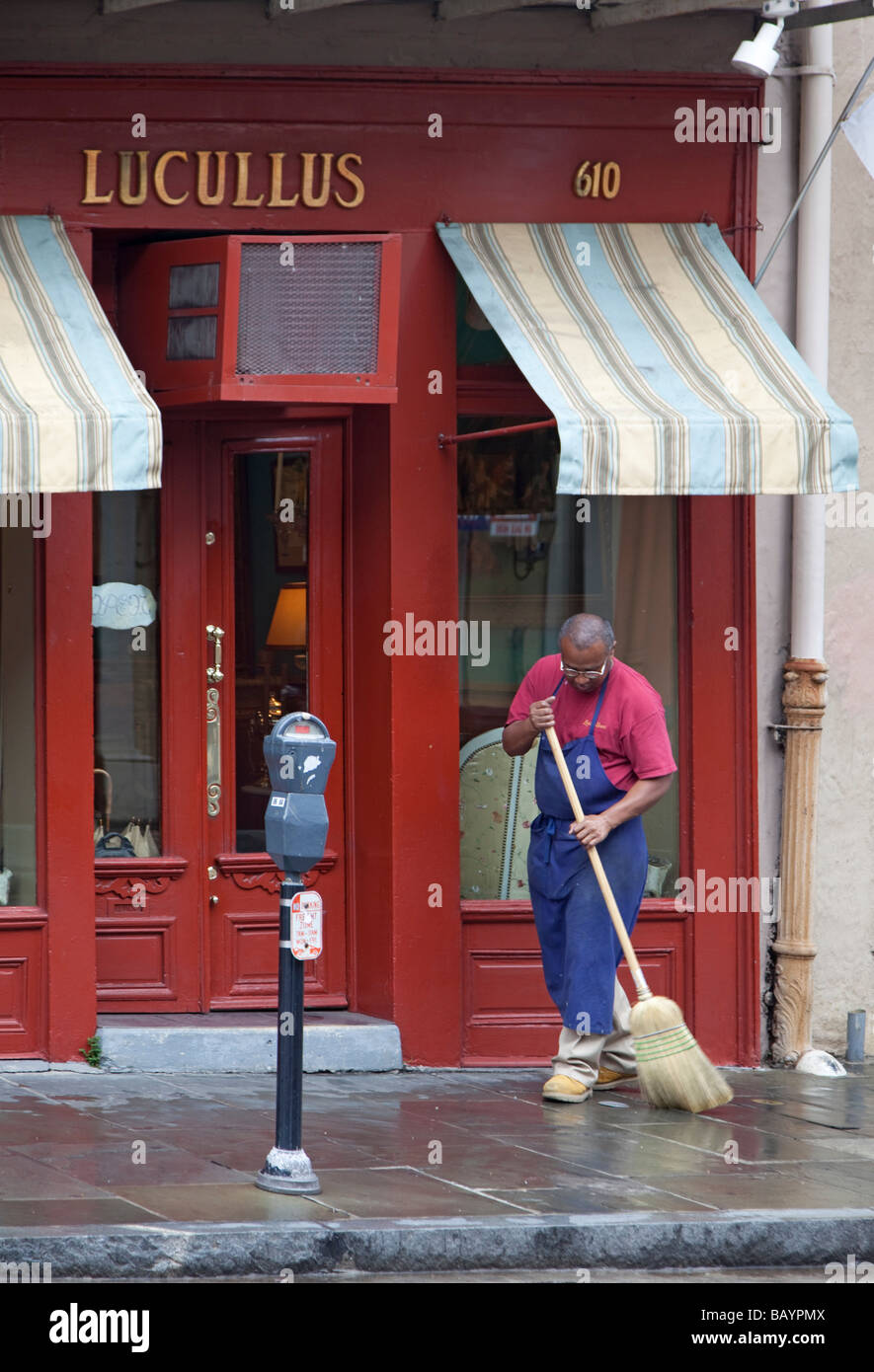 New Orleans Louisiana A Mann fegt dem Bürgersteig vor Lucullus ein Antiquitätengeschäft im French Quarter Stockfoto