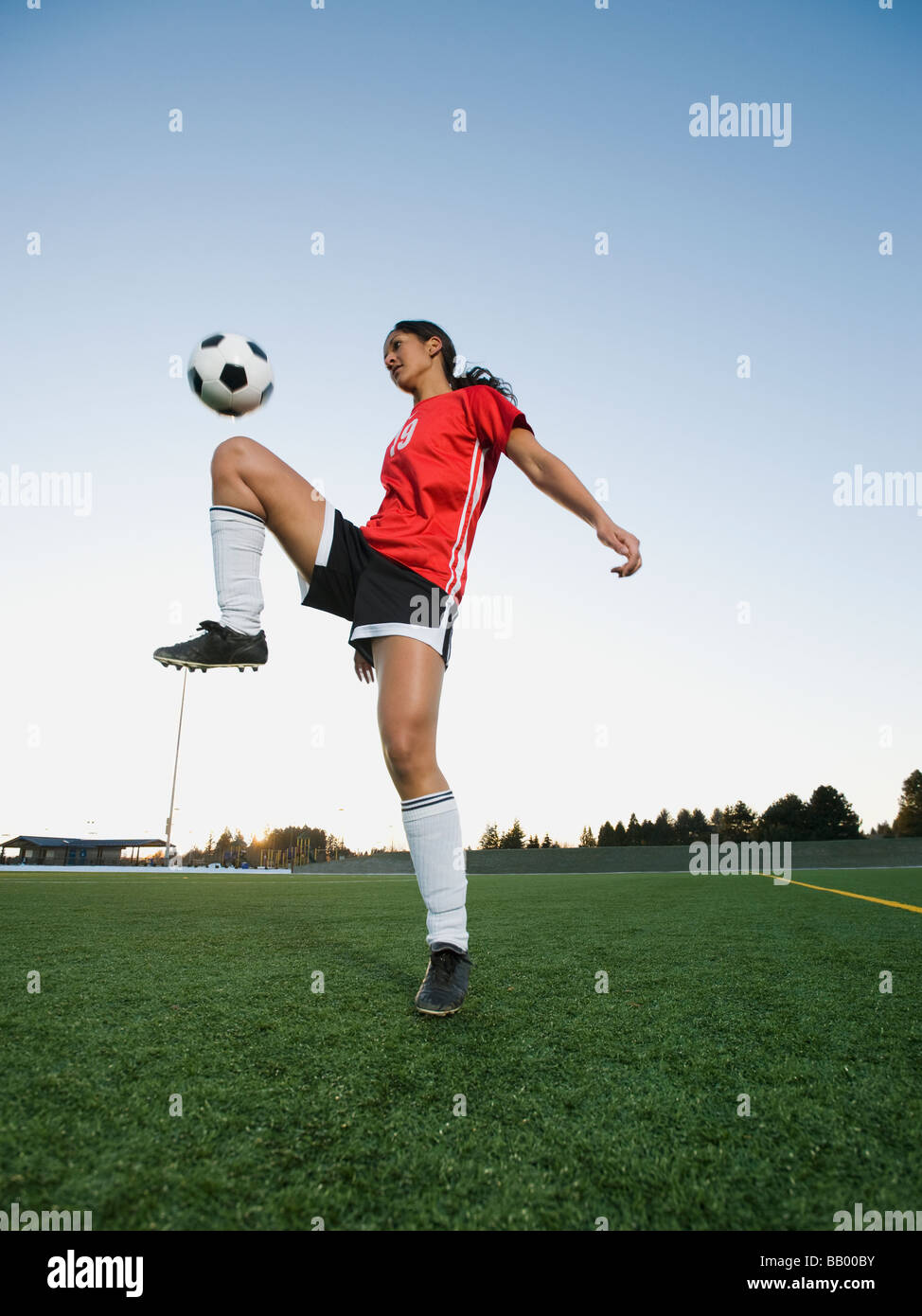 Gemischte Rassen Frau Prellen Fußball auf Knie Stockfoto