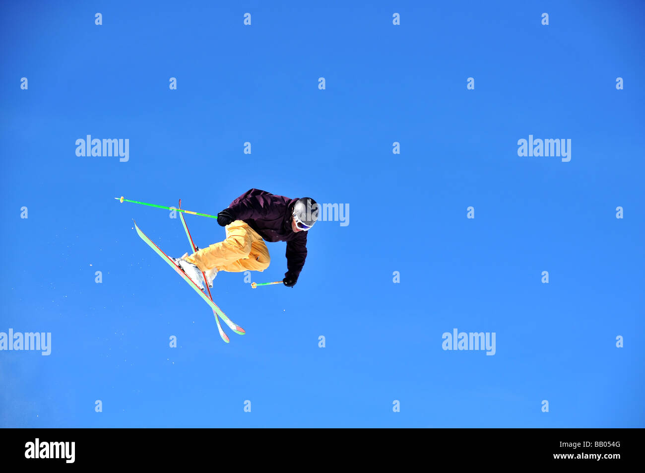 ein Skifahrer springen vor einem klaren blauen Himmel Schneeflocken auf seinem Weg folgen Stockfoto