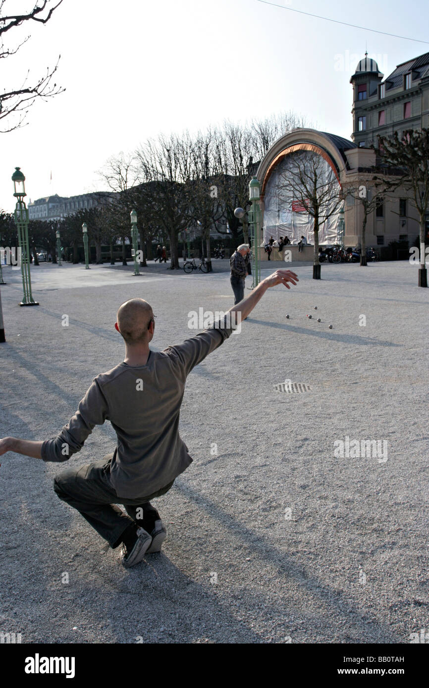Ein Mann wirft eine Stahlkugel anmutig in ein outdoor-Spiel Boule Bowl in Luzern, Schweiz. Stockfoto